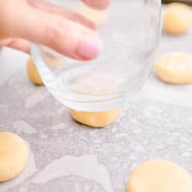 Cookie dough is being pressed with a glass.