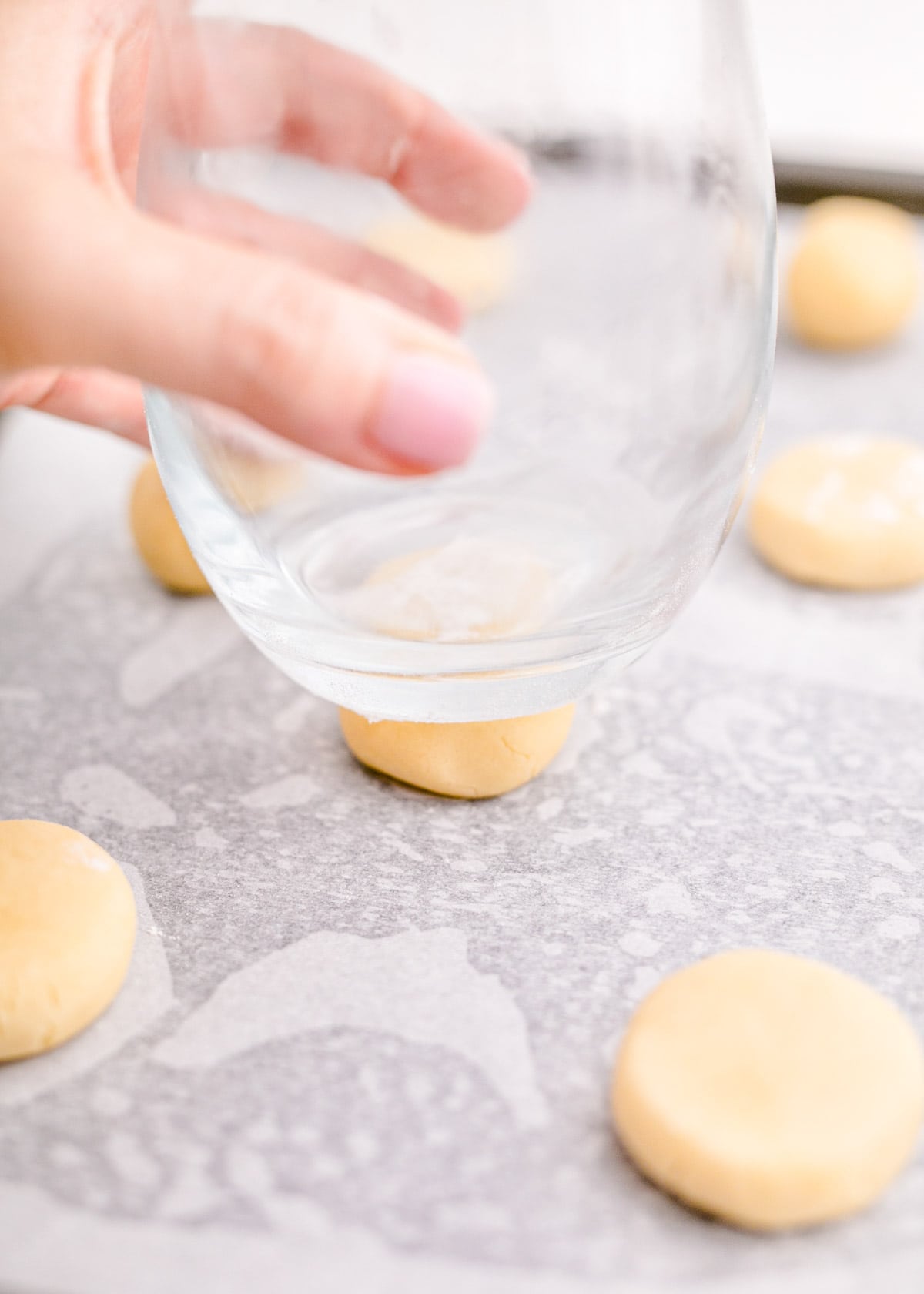 Cookie dough is being pressed with a glass.