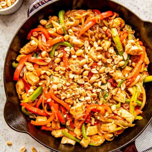 finished kung pao chicken in a cast iron skillet topped with chopped peanuts