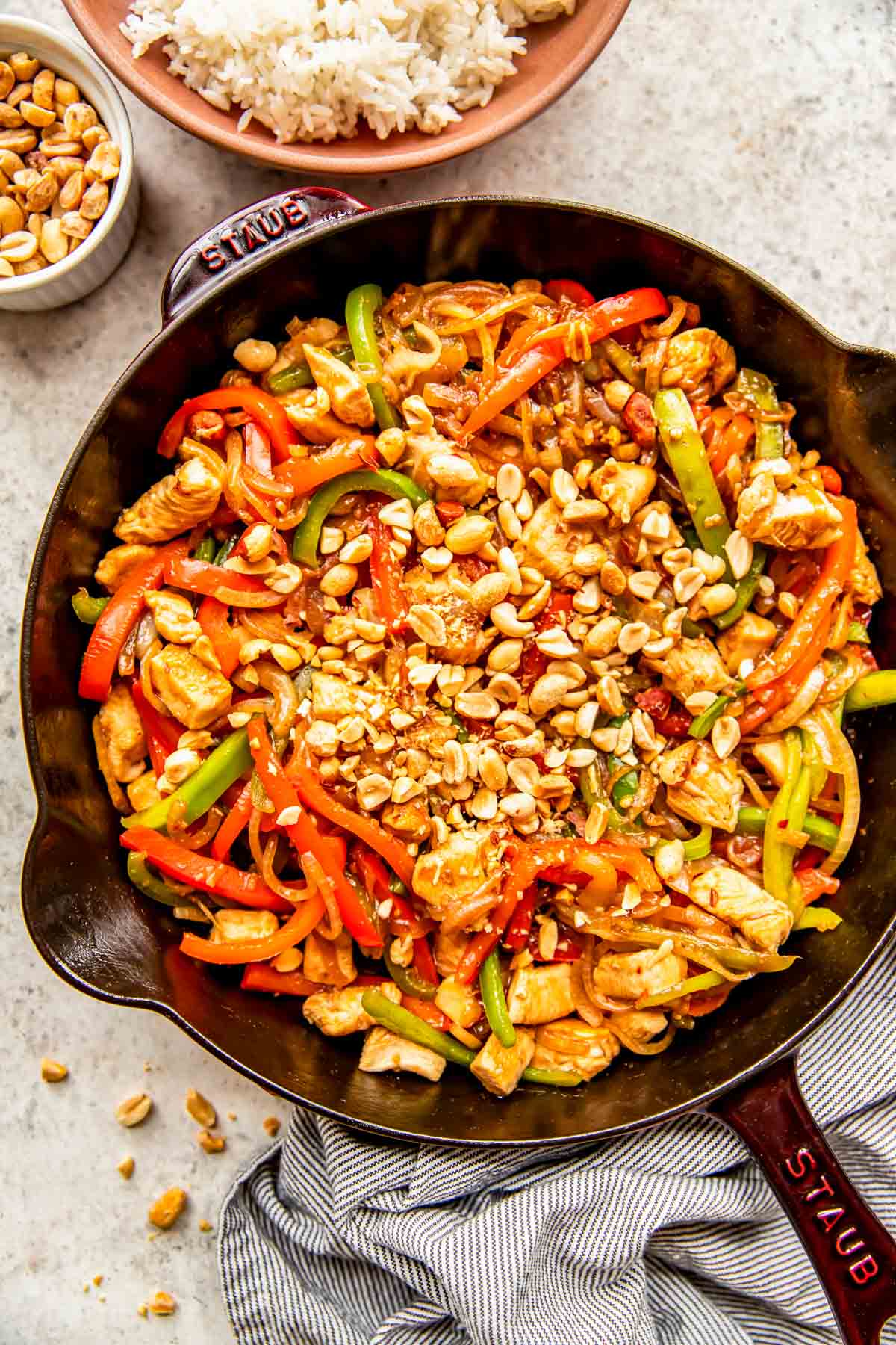 finished kung pao chicken in a cast iron skillet topped with chopped peanuts