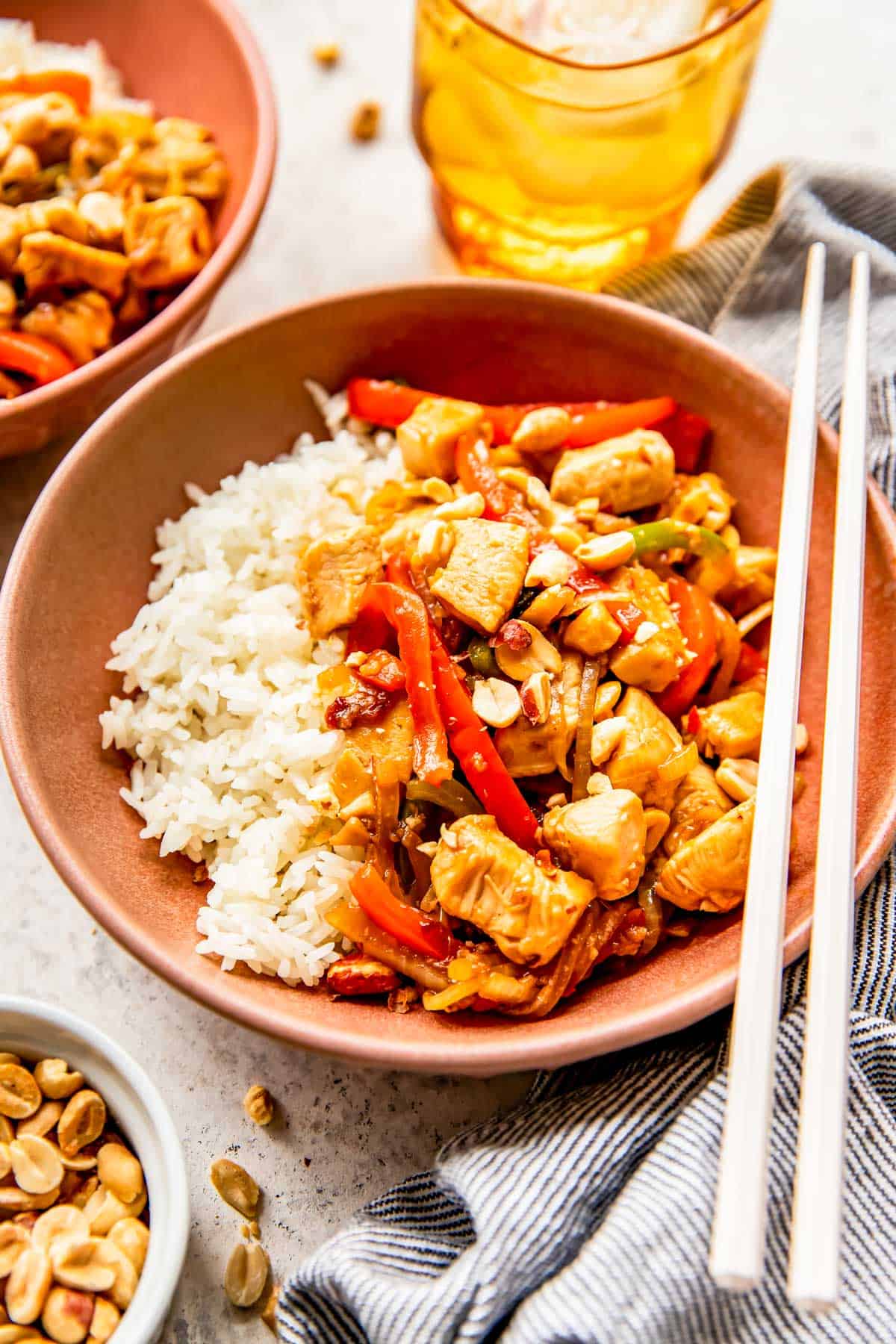 kung pao chicken in a pink bowl with white rice and plastic chopsticks