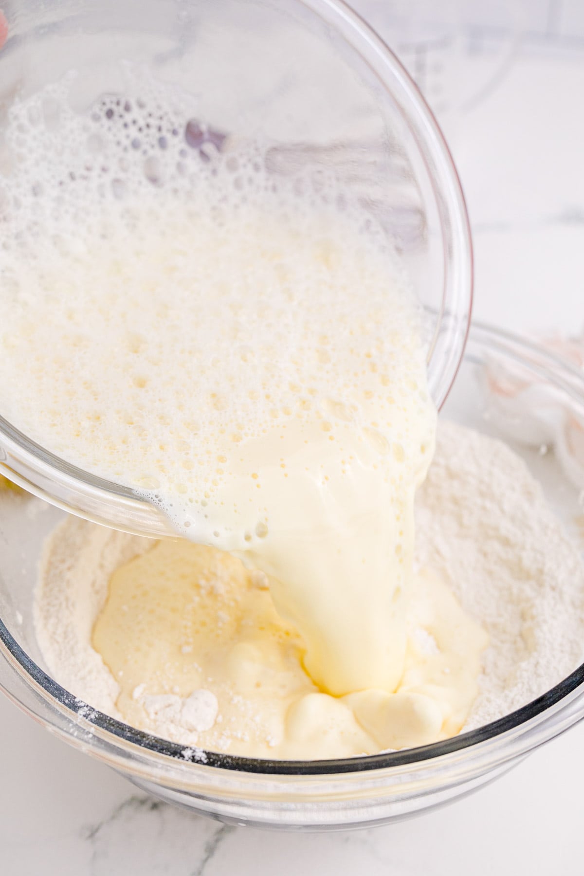 pouring wet ingredients into dry ingredients in a clear bowl