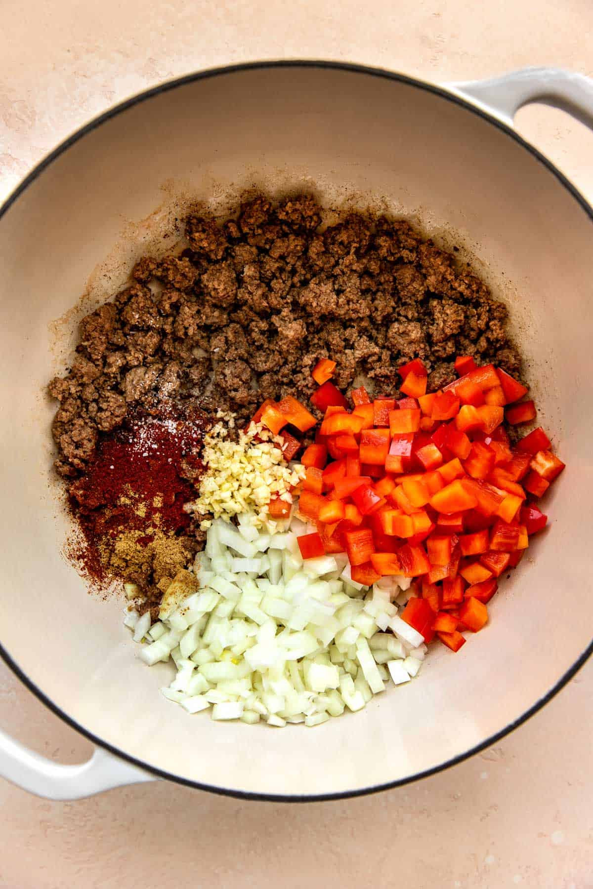 crumbled ground beef with seasonings and vegetables in a cast iron skillet