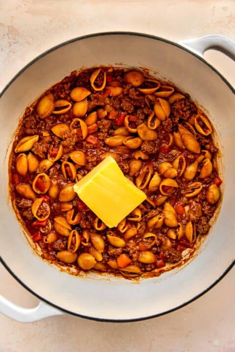 a block of velveeta cheese added to the finished pasta dish