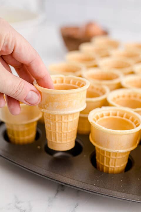 placing ice cream cones into a mini muffin tin