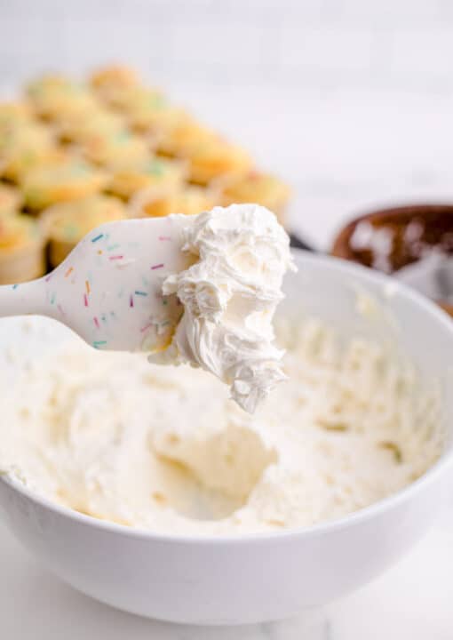 a white silicone spatula has buttercream frosting at the tip of it
