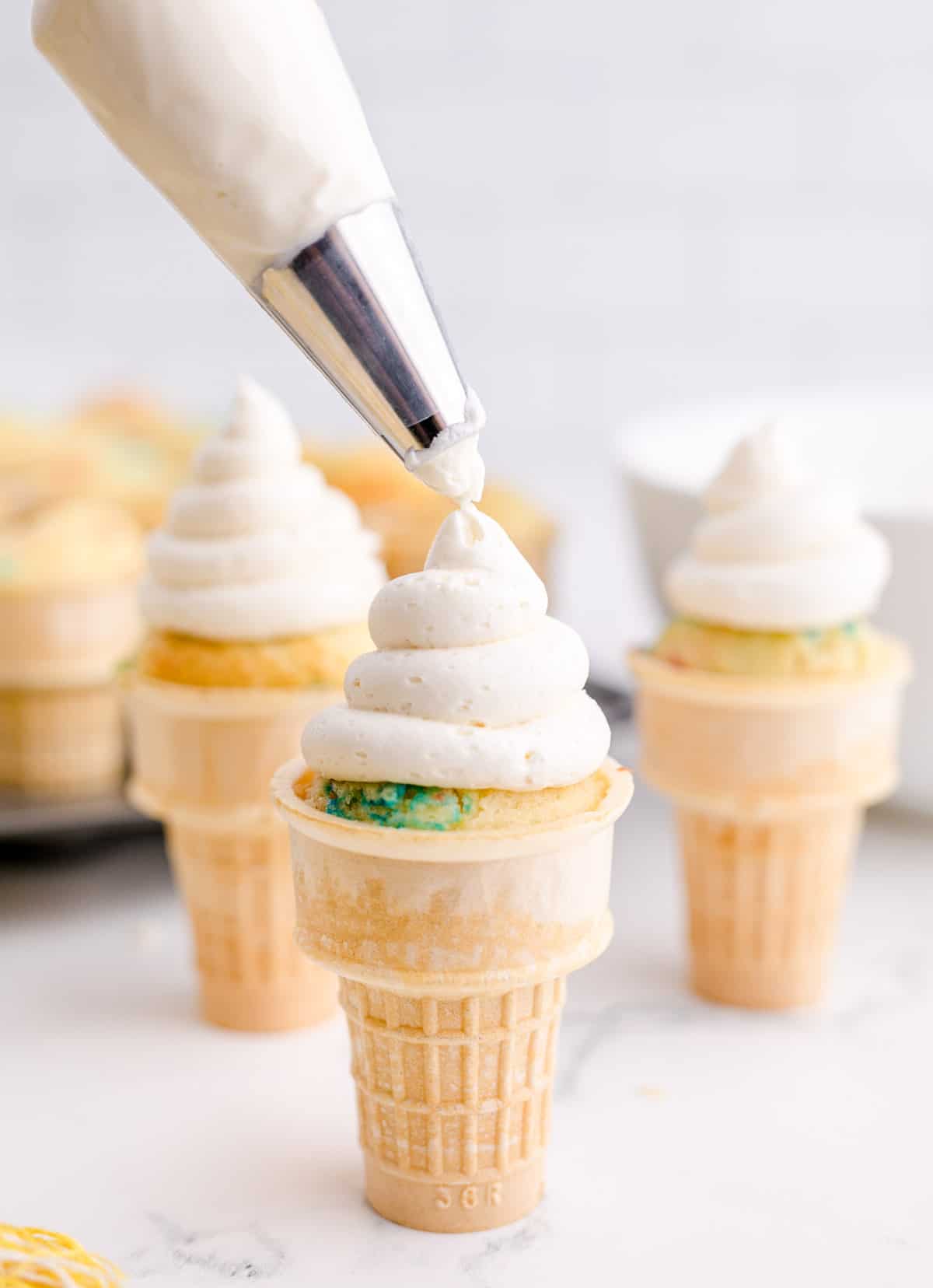 a swirl of buttercream is piped onto ice cream cone cupcakes