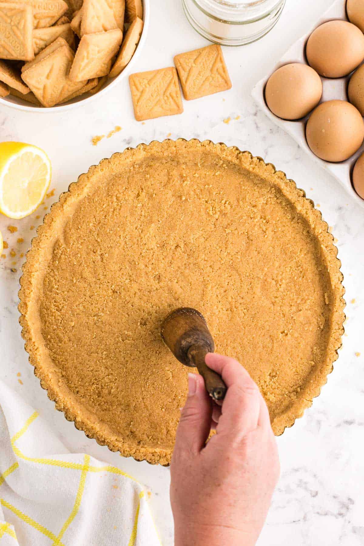 pressing shortbread crumbs into a metal tart pan