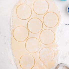 cookie dough with circles cut out in the dough on a lightly floured work surface