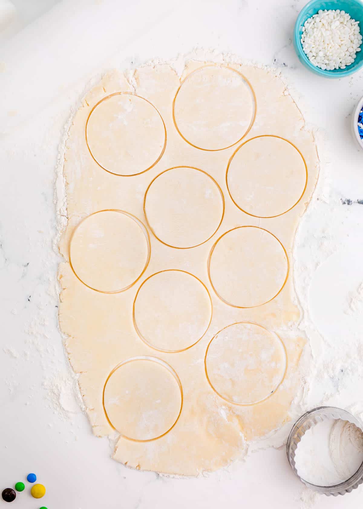 cookie dough with circles cut out in the dough on a lightly floured work surface