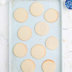 circular sugar cookies baked on a speckled blue baking sheet