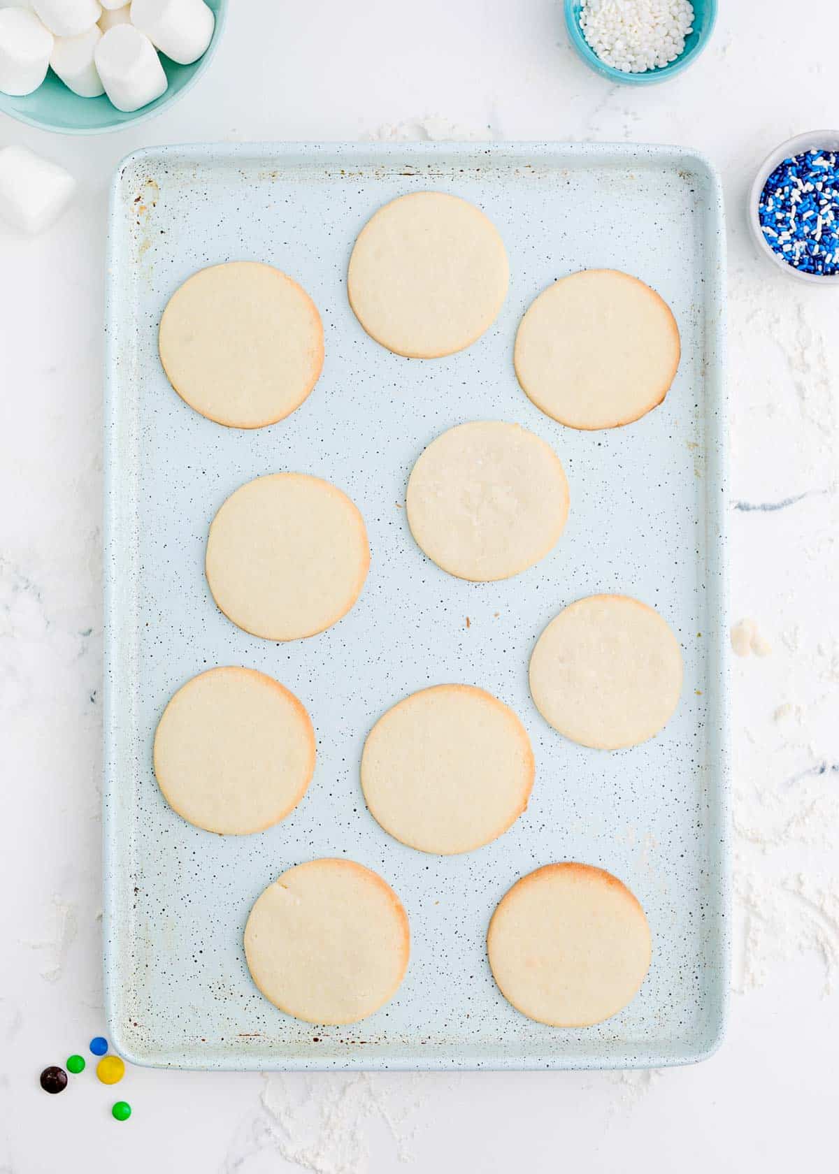 circular sugar cookies baked on a speckled blue baking sheet