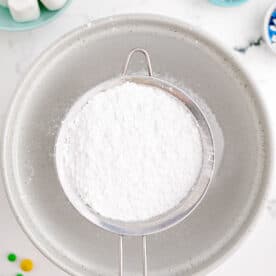 powdered sugar in a sifter over a large bowl