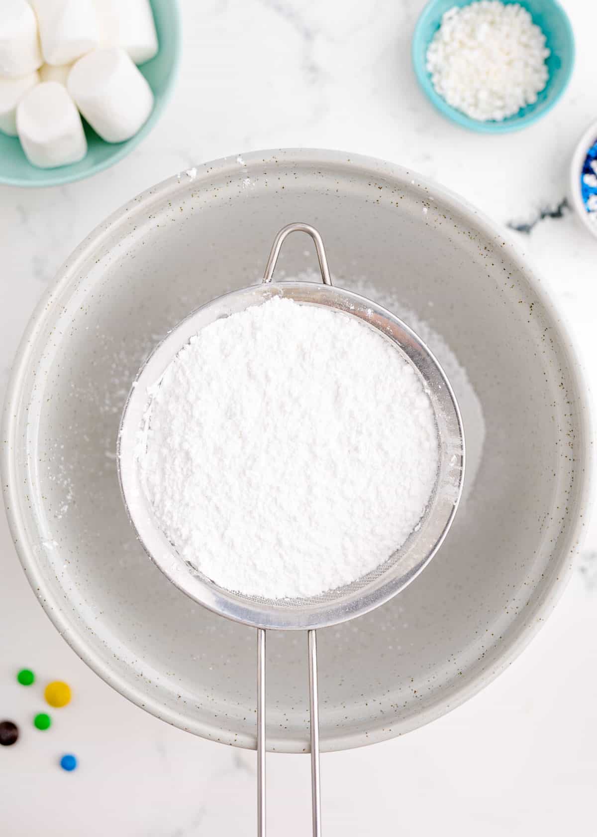 powdered sugar in a sifter over a large bowl