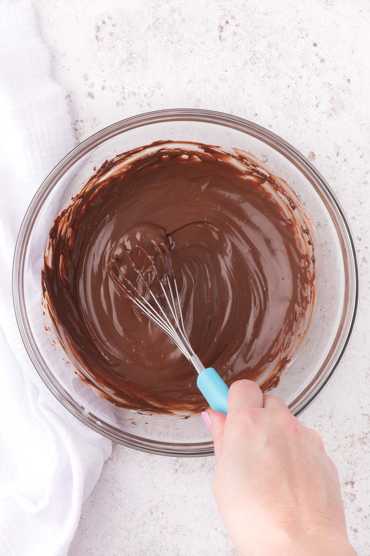 whisking together chocolate ganache in a glass bowl