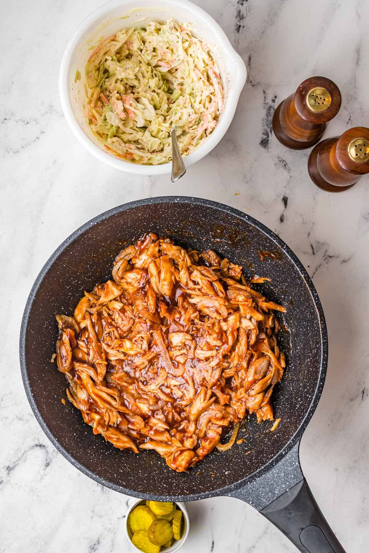 A black skillet is filled with bbq chicken.