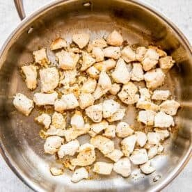 chicken in a stainless steel pan being cooked and browned