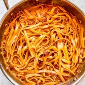 linguine pasta cooked through and in a cream sauce in a stainless steel skillet