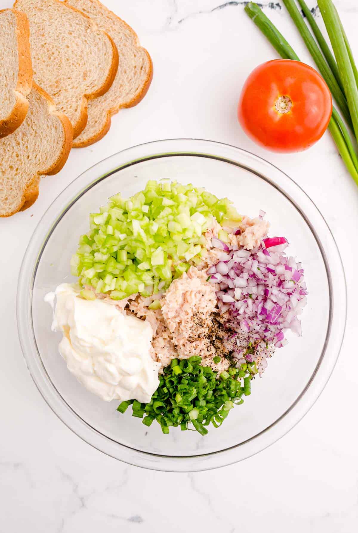 mayo, chopped celery, chopped red onions, green onions, pepper, and tuna fish in a clear bowl