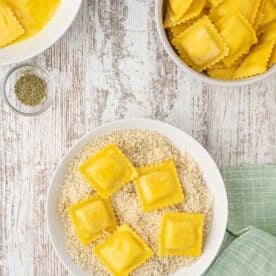 egg washed ravioli sits on top of a panko breadcrumb mixture