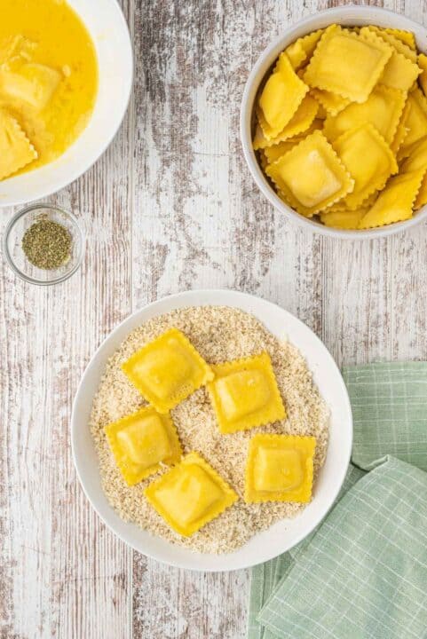 egg washed ravioli sits on top of a panko breadcrumb mixture