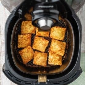 browned and crispy air fried ravioli in the basket of an air fryer