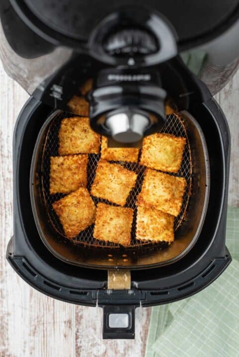browned and crispy air fried ravioli in the basket of an air fryer