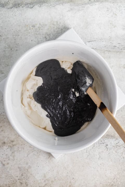black sesame paste added to a white bowl with the heavy cream