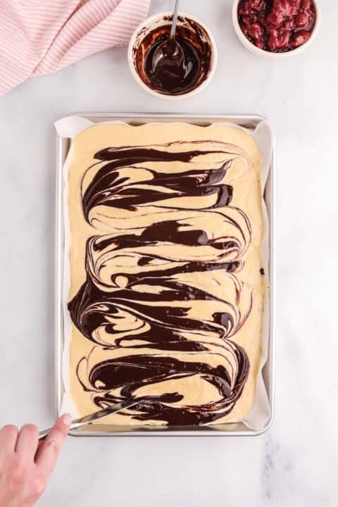 chocolate sauce being swirled into pancake batter with a butter knife