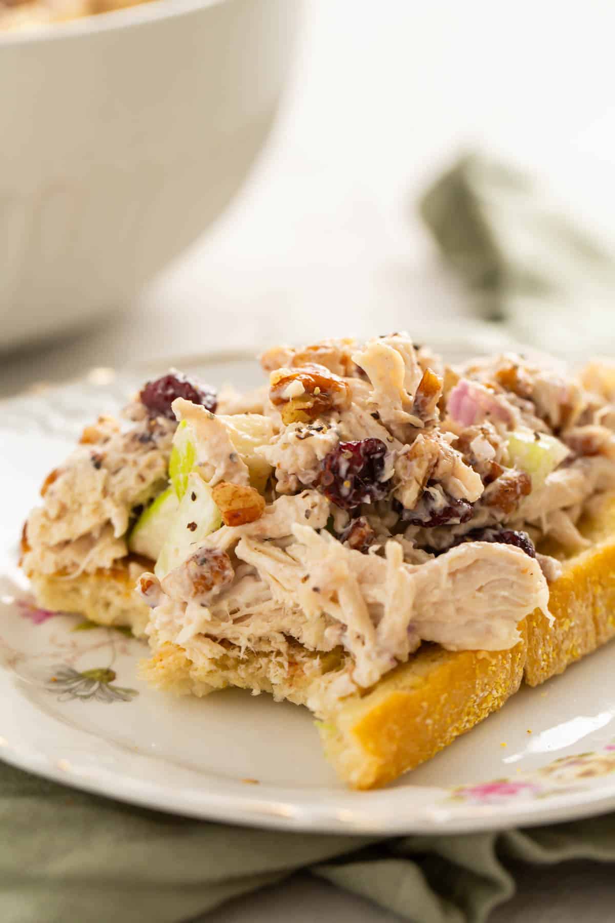 cranberry pecan chicken salad sits on top of bread that has been bitten into