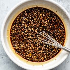 soy sauce-based sauce with minced garlic and ginger in a bowl with a metal whisk