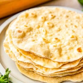 homemade flour tortillas are stacked on a plate