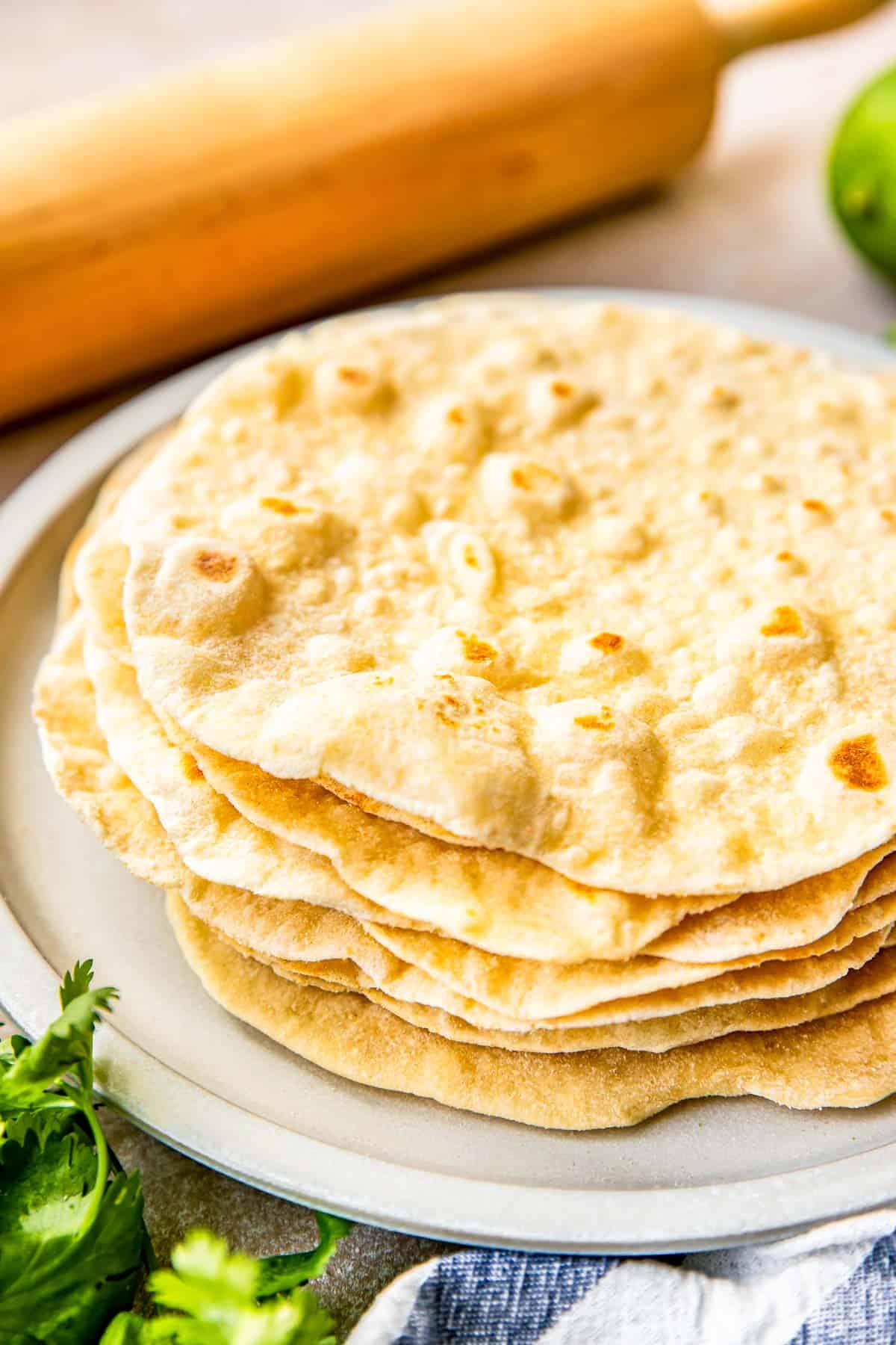 homemade flour tortillas are stacked on a plate