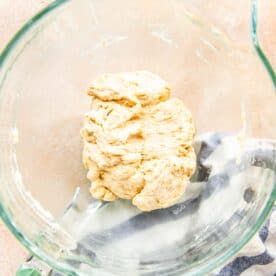 a ball of dough is in a glass stand mixer bowl