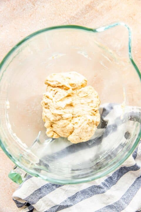 a ball of dough is in a glass stand mixer bowl