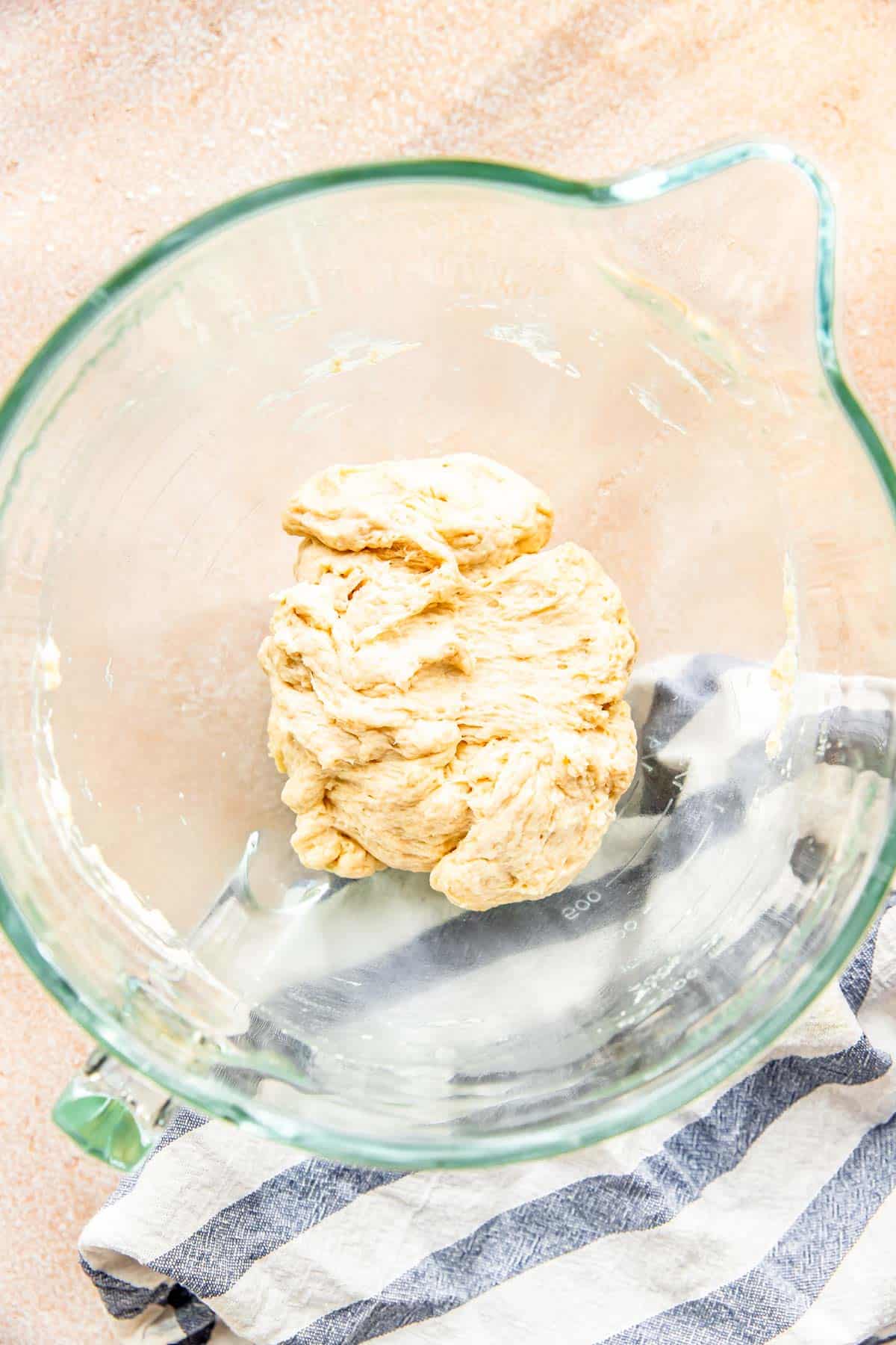 a ball of dough is in a glass stand mixer bowl