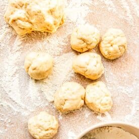 dough balls are formed on a lightly floured work surface next to a larger dough ball