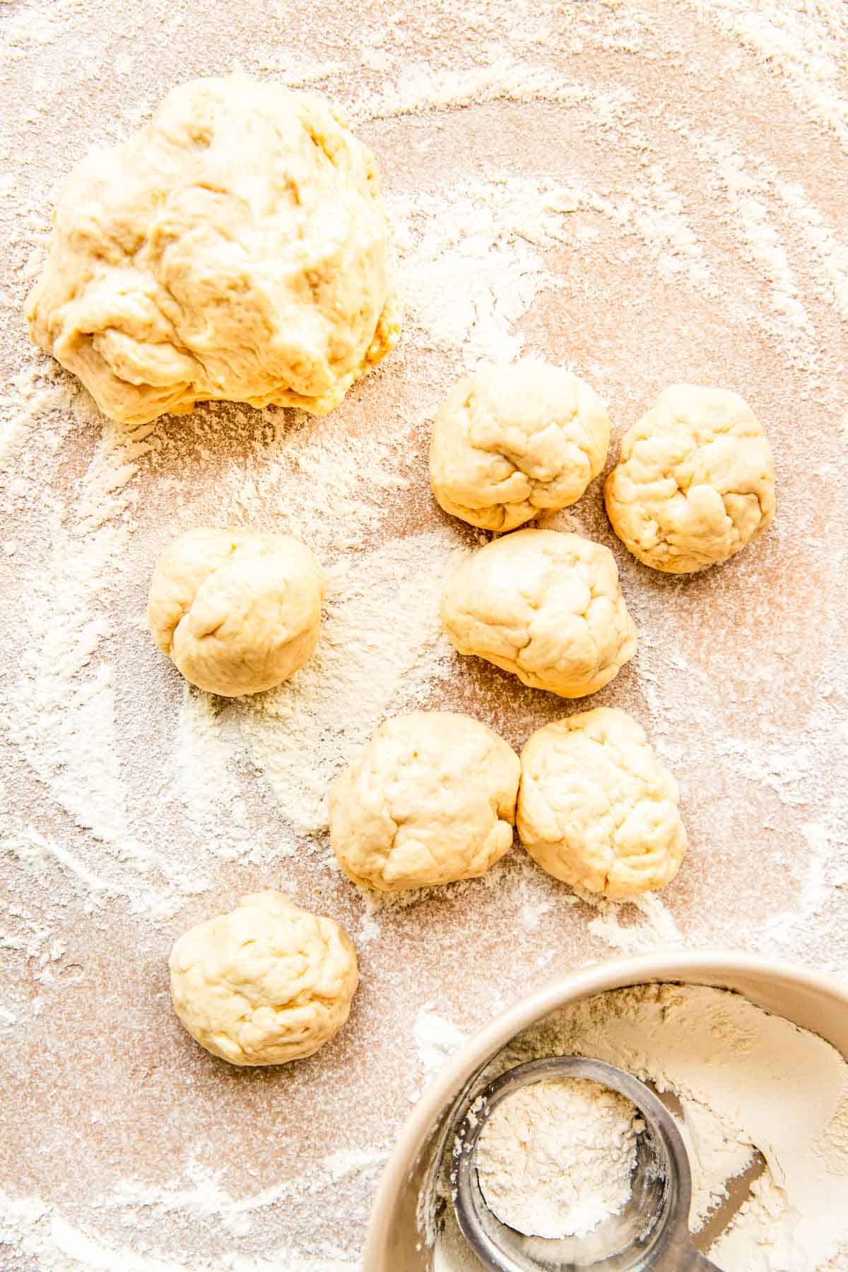 dough balls are formed on a lightly floured work surface next to a larger dough ball