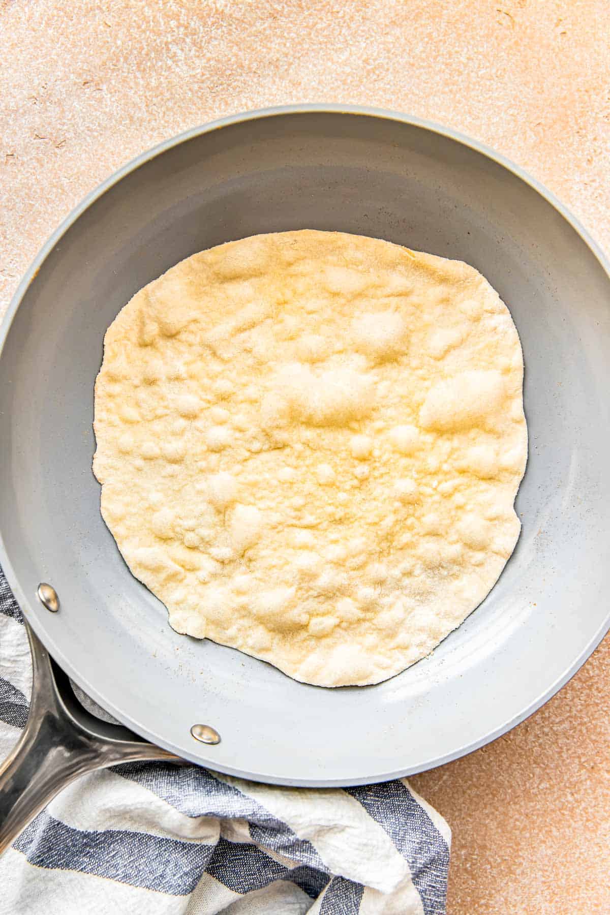 a bubbling surface of a flour tortilla is in a nonstick skillet