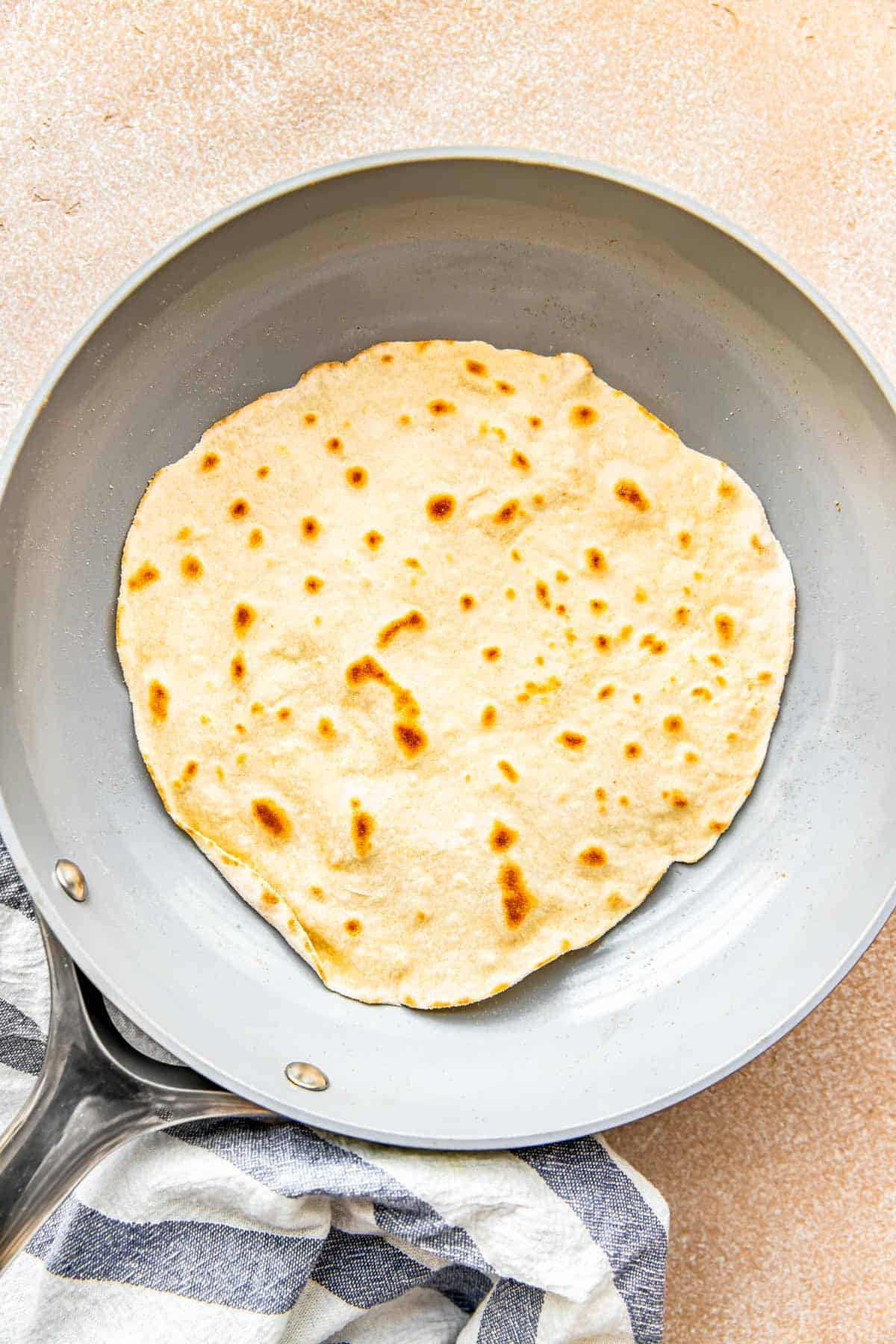 a flour tortilla with brown spots all over is in a nonstick skillet