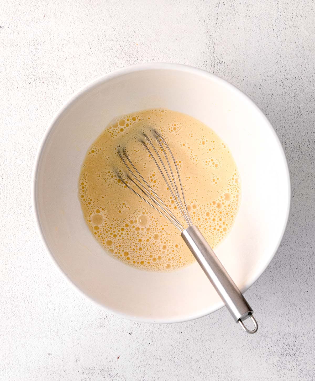 wet batter in a white bowl with a metal whisk