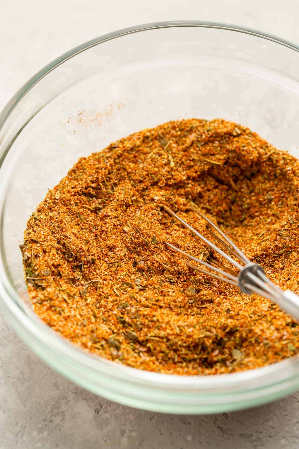 up close photograph of seafood seasoning in a glass bowl with a metal whisk