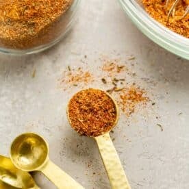 seafood seasoning on a gold 1/2 teaspoon spoon next to seafood seasoning that has spilled onto the table