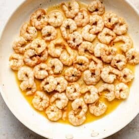 shrimp being cooked in a skillet with butter