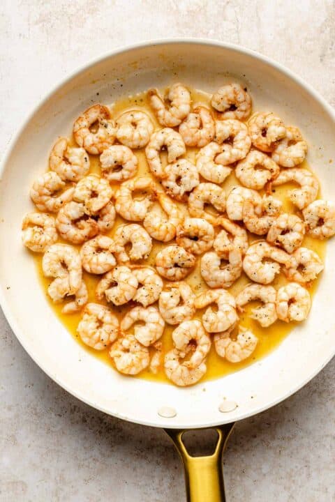 shrimp being cooked in a skillet with butter