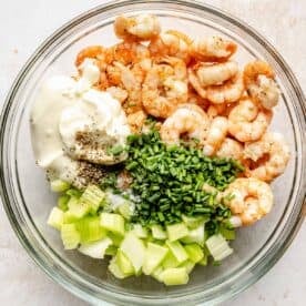 shrimp, mayo, black pepper, celery, chives, and seasonings all in a clear bowl