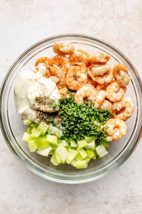 shrimp, mayo, black pepper, celery, chives, and seasonings all in a clear bowl