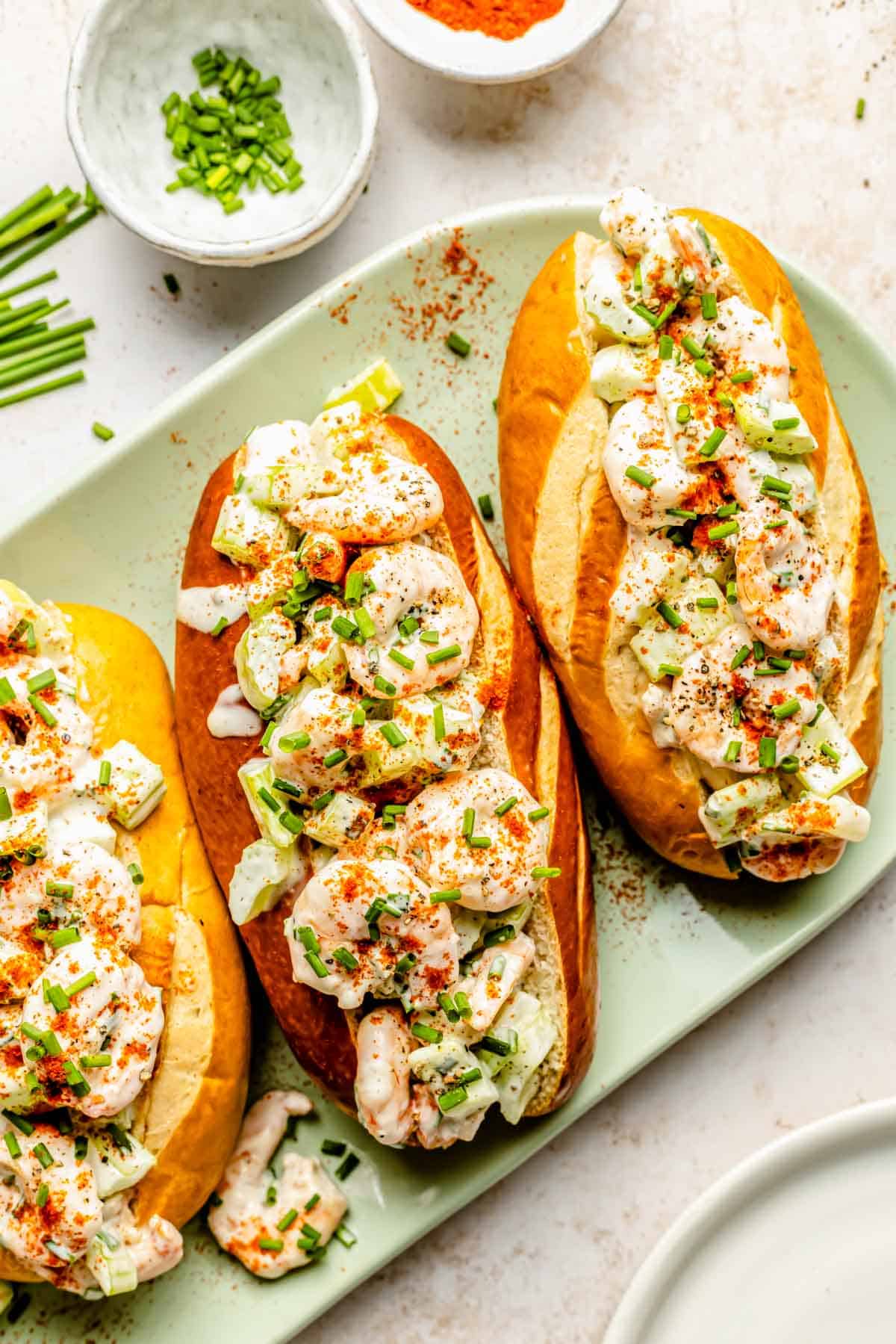 overhead image of shrimp rolls on a green plate sprinkled with fresh chives on top