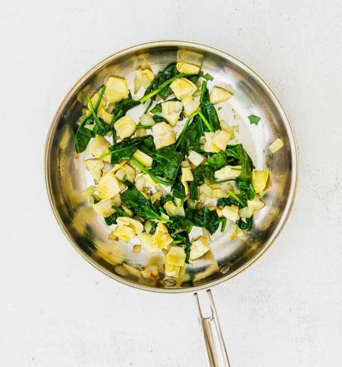 artichoke and spinach cooked in a metal skillet