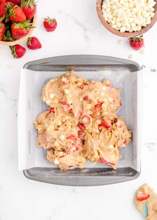 strawberry blondie batter added to a metal baking dish with parchment paper